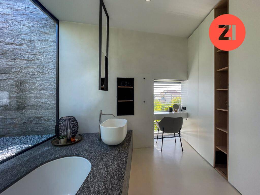 Modernes Badezimmer mit freistehender Badewanne, großem Fenster und integriertem Schminkbereich.