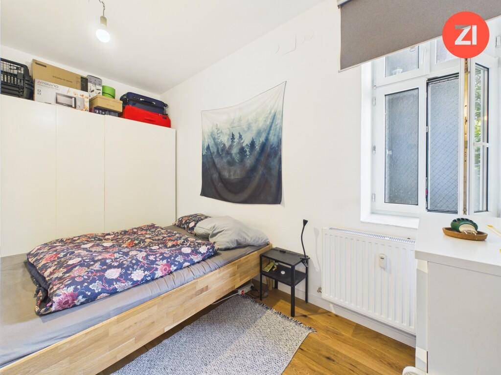Schlafzimmer mit Holzboden, Einbauschrank und einem Fenster, das viel Tageslicht hereinlässt.