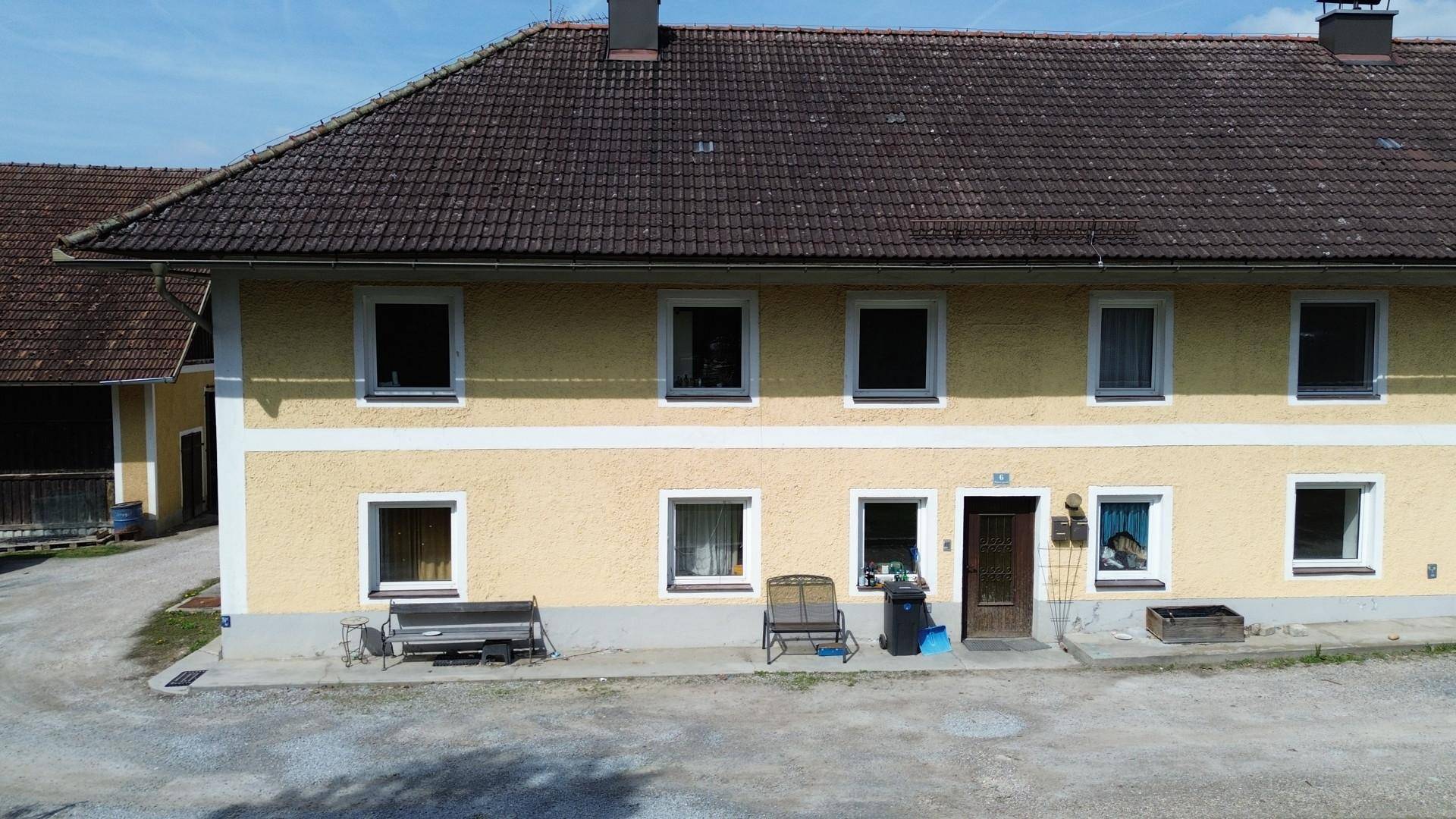 Vorderansicht eines traditionellen gelben Gebäudes mit braunem Ziegeldach und mehreren Fenstern.