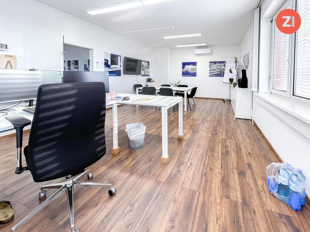 Helles und geräumiges Büro mit mehreren Arbeitsplätzen, Laminatboden und Klimaanlage an der Wand.