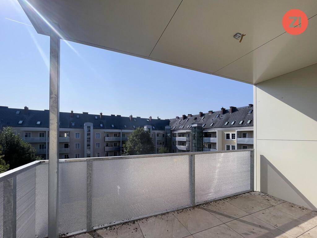 Geräumiger Balkon mit Fliesenboden und Blick auf die umliegenden Wohngebäude.