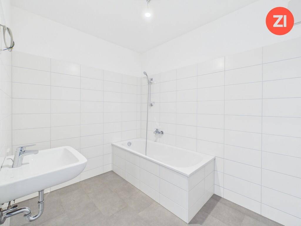 Modernes Badezimmer mit weißen Fliesen, Badewanne und einem einzelnen Waschbecken.