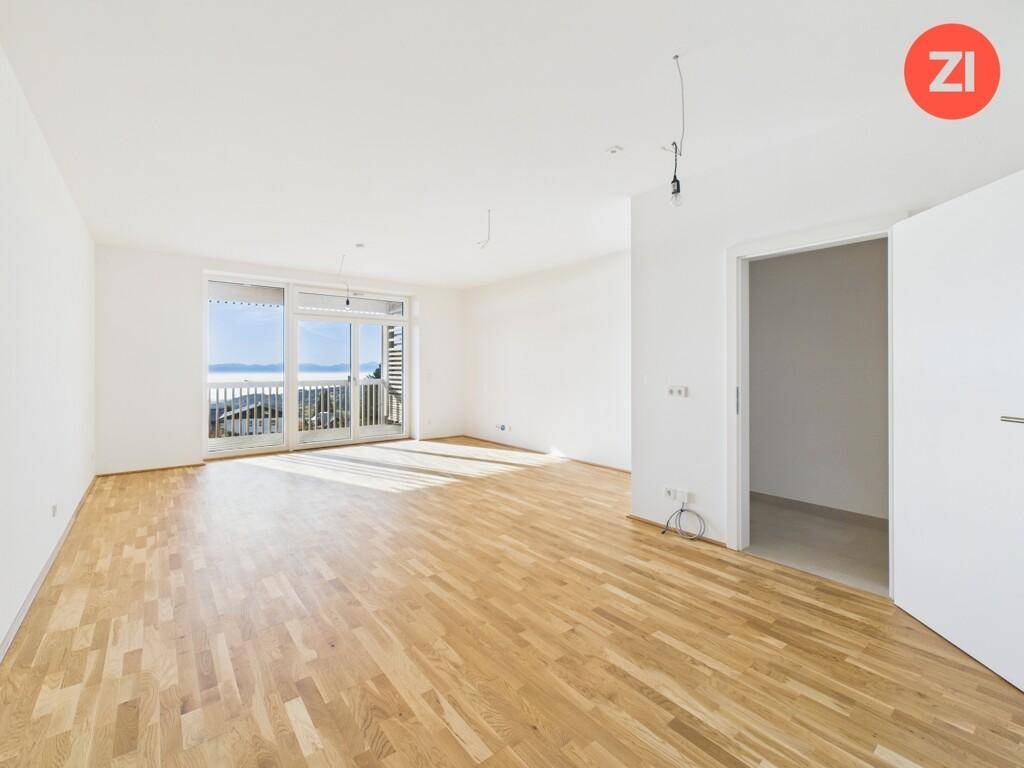 Lichtdurchflutetes Wohnzimmer mit Holzboden und Zugang zu einem Balkon mit Weitblick.