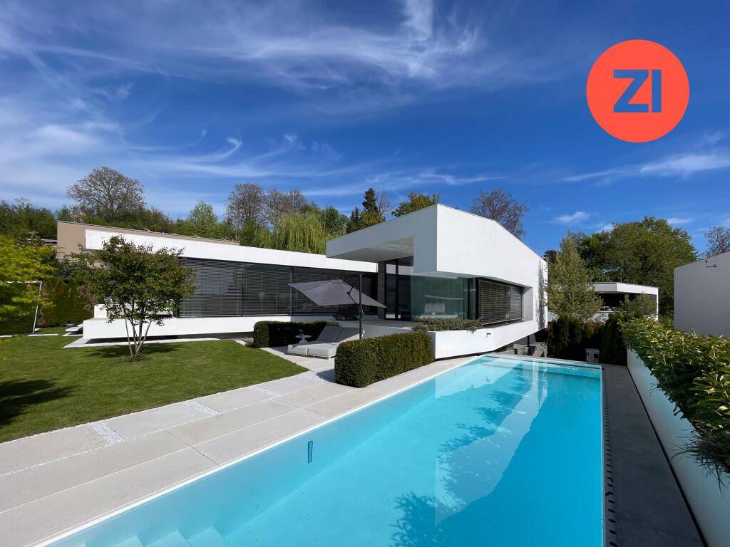 Moderne Villa mit großem Pool und weitläufigem Garten, eingebettet in eine grüne Umgebung.