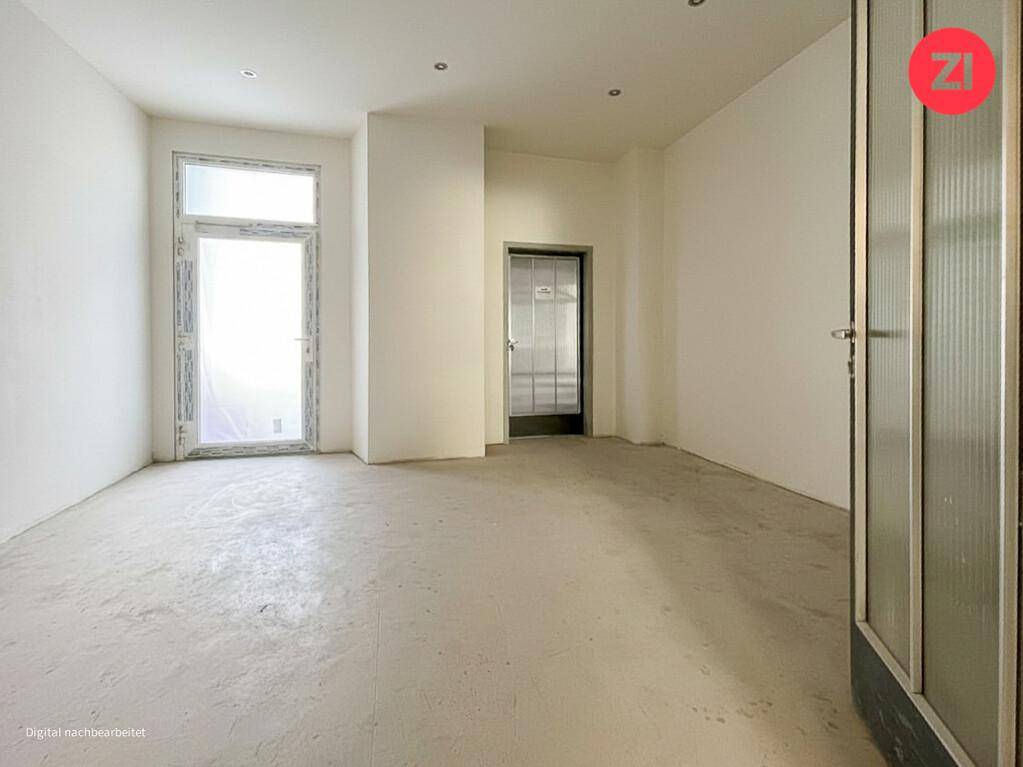 Heller Raum mit Betonboden, weißen Wänden und großem Fenster, ideal für ein Büro oder Atelier.