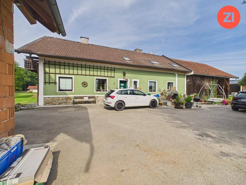 Traditionelles Landhaus mit grün gestrichener Fassade und großem Vorplatz.