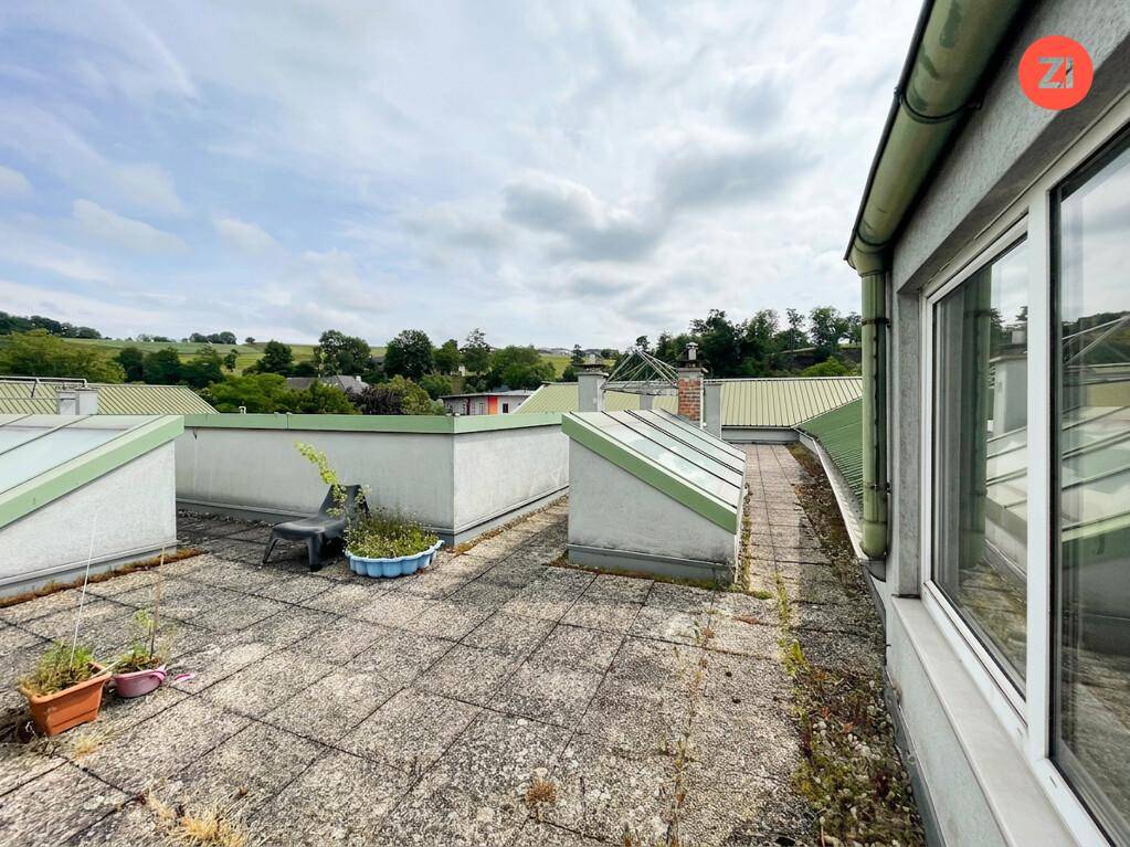 Weitläufige Dachterrasse mit Fliesenboden und Blick auf die umliegende Landschaft.