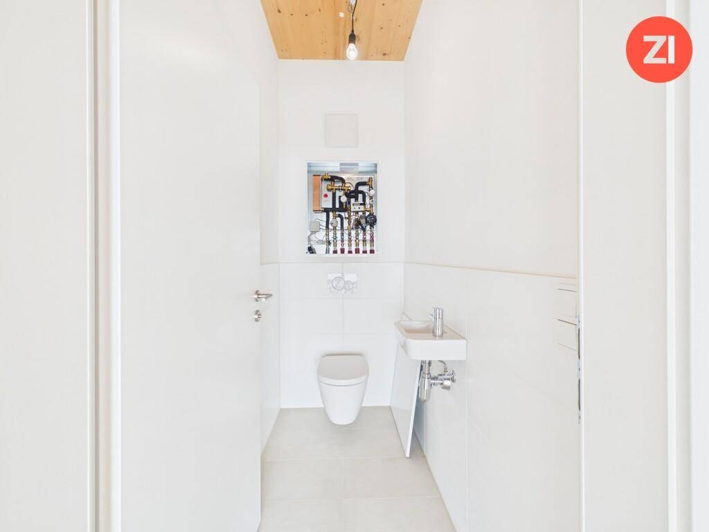 Kleines Gäste-WC mit wandhängender Toilette und Waschbecken, inklusive Technikzugang.