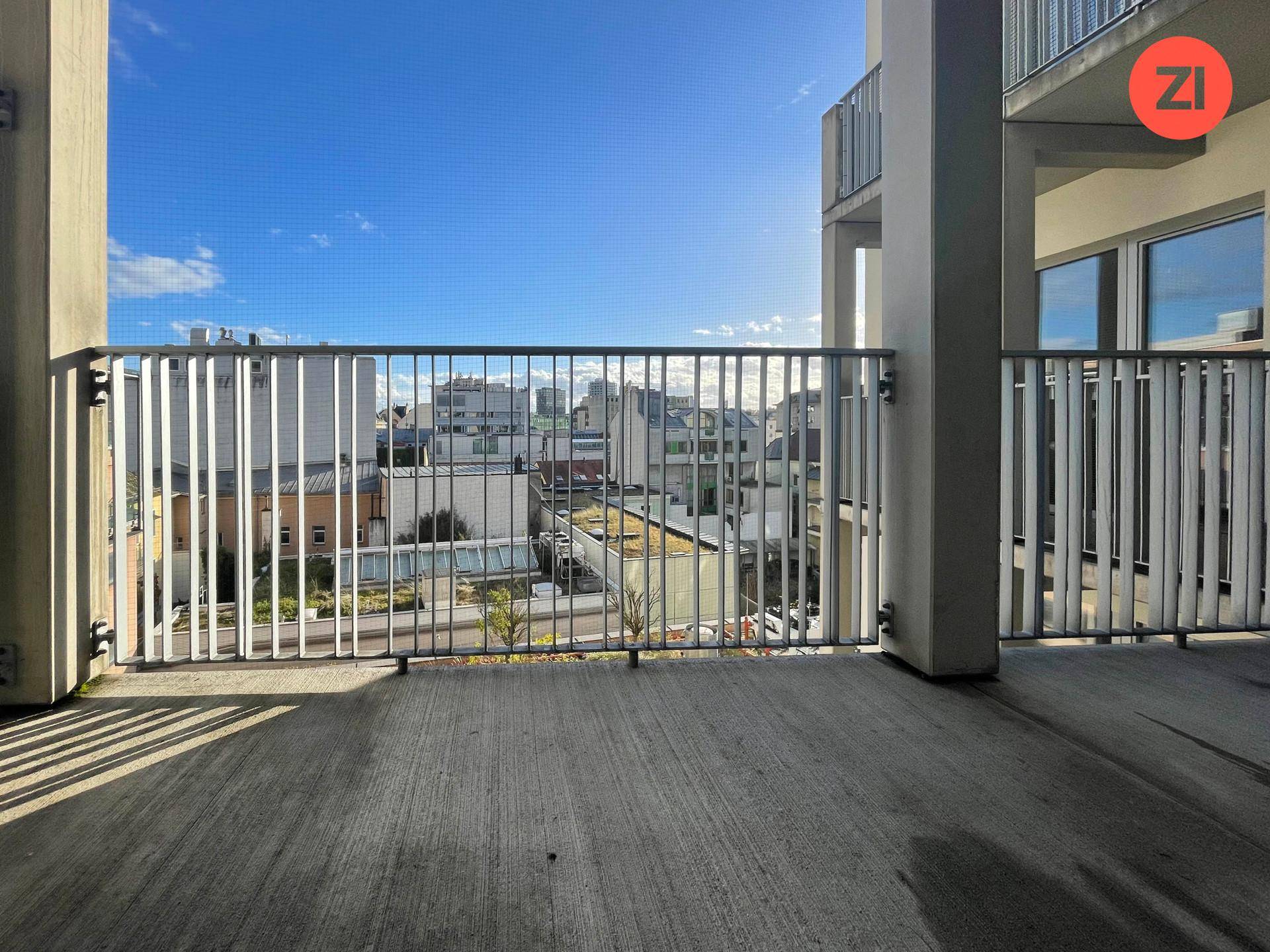 Geräumiger Balkon mit Metallgeländer und Blick auf die umliegende Stadtlandschaft.