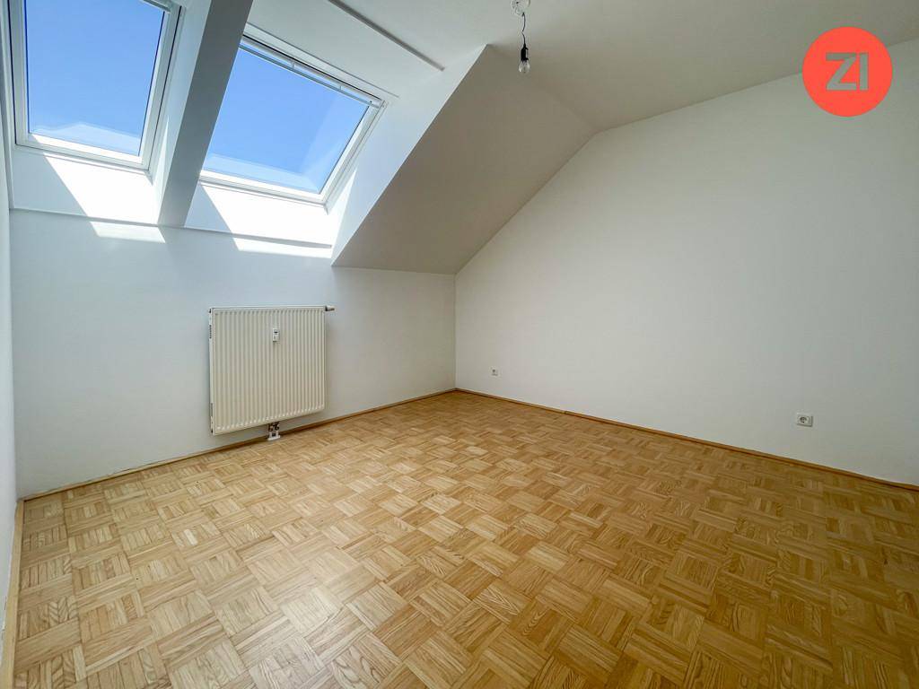 Helles Dachzimmer mit Holzboden, Dachschrägen und viel Tageslicht durch die beiden Dachfenster.