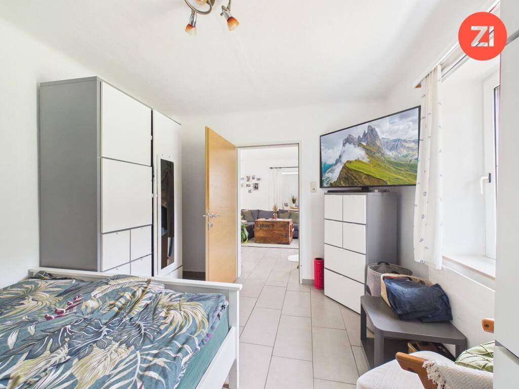 Schlafzimmer mit Fliesenboden, Kleiderschrank und Zugang zum Wohnbereich.