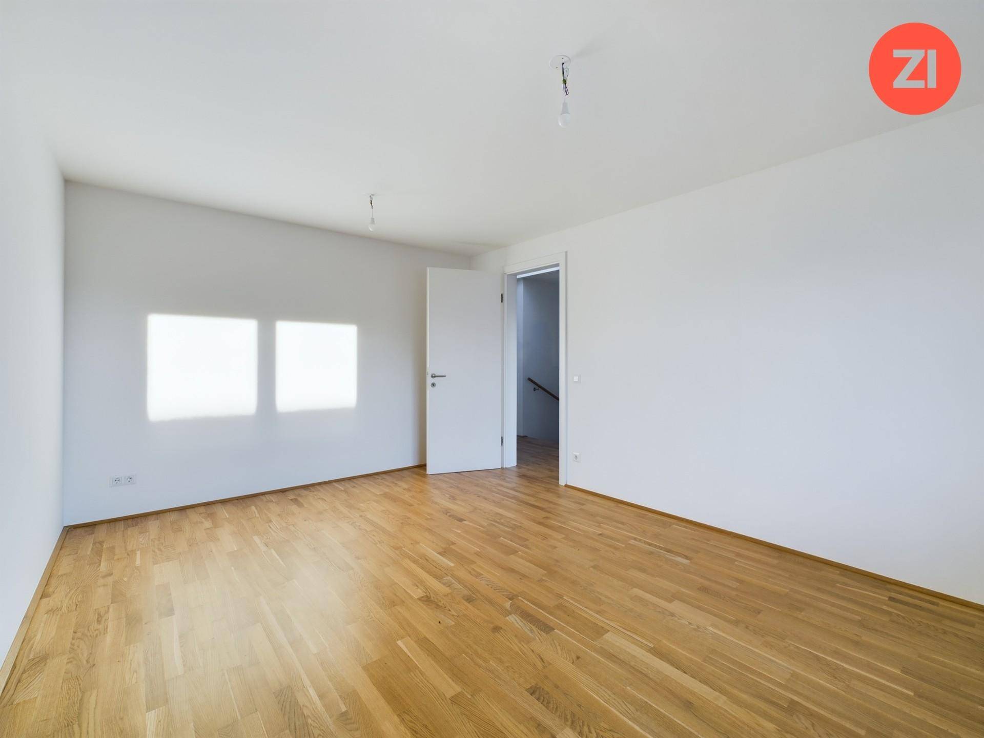 Großes, helles Schlafzimmer mit Parkettboden und viel Tageslicht, ideal für individuelle Einrichtung.