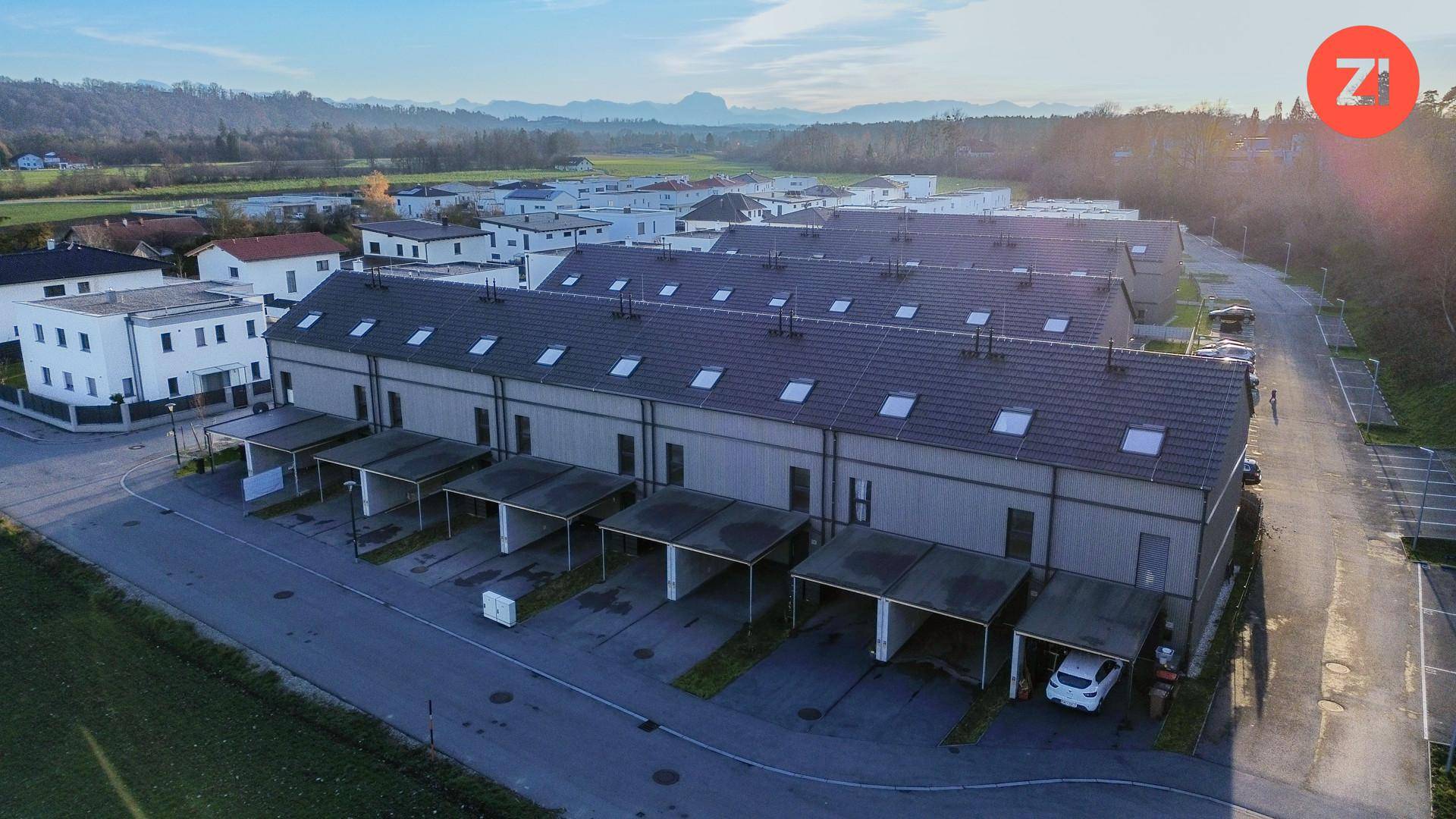 Luftaufnahme einer modernen Reihenhaussiedlung mit Carports und Dachfenstern.