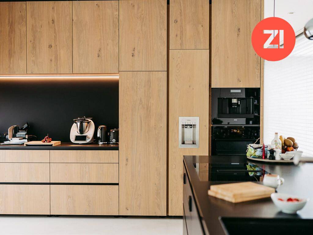 Moderne Küche mit Holzfronten, integrierten Geräten und schwarzer Arbeitsplatte.