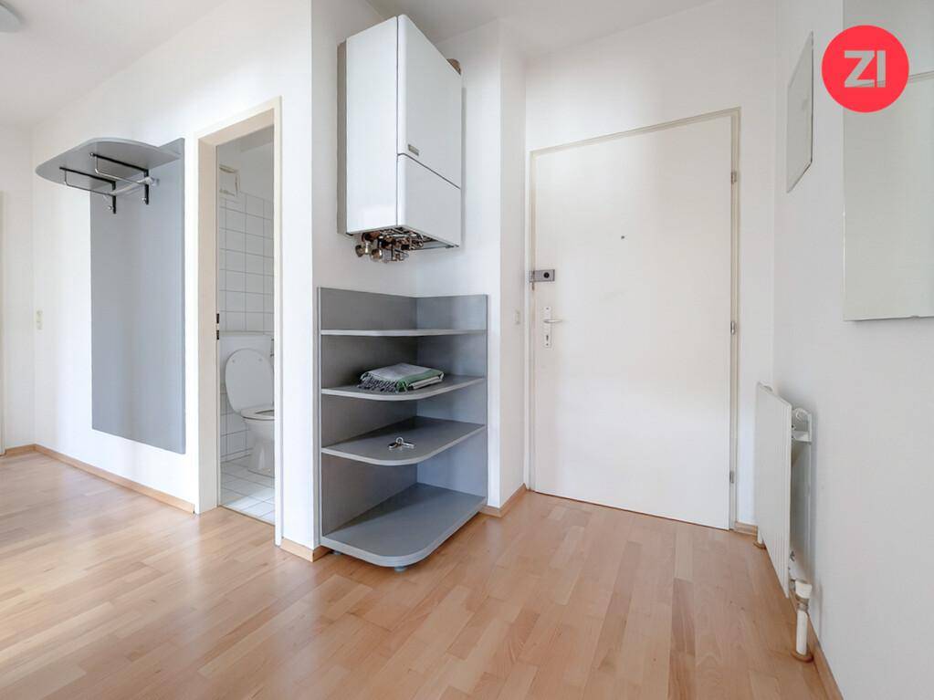 Eingangsbereich mit Holzfußboden, praktischem Regal und Zugang zu einem Badezimmer.