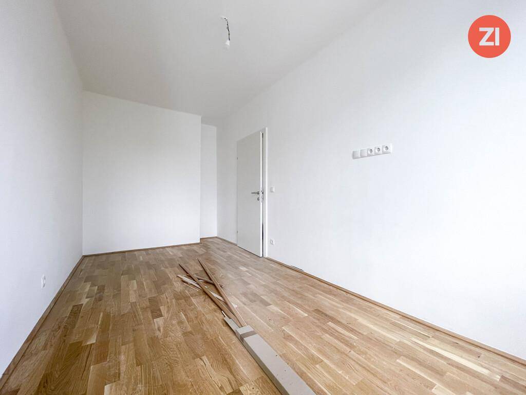 Leeres Zimmer mit hellem Holzparkettboden und weißen Wänden, bereit zur individuellen Gestaltung.