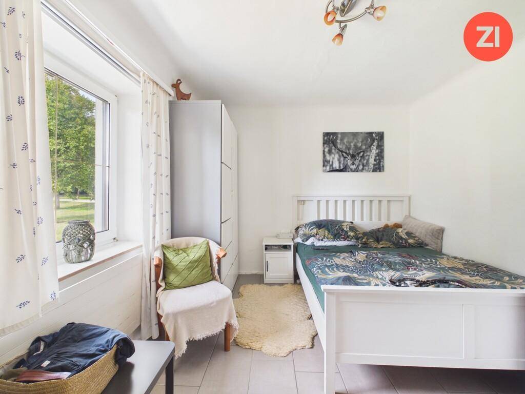 Helles Schlafzimmer mit Einzelbett, Kleiderschrank und Fenster mit Blick ins Grüne.