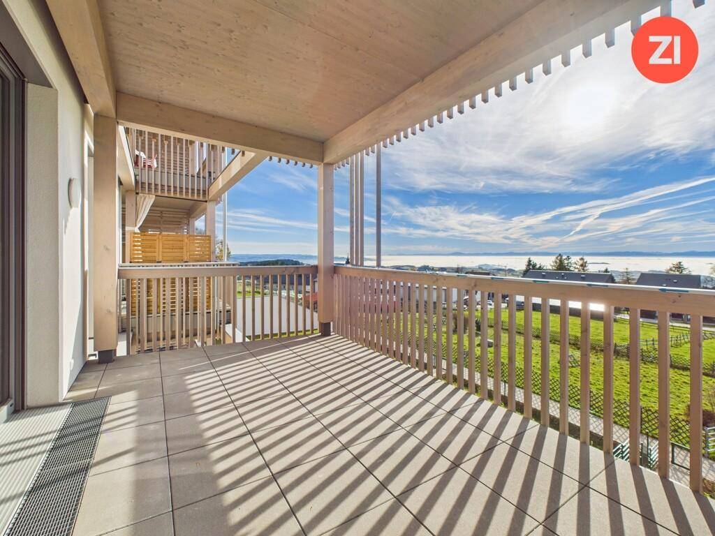 Großer Balkon mit Fliesenboden und Holzgeländer, bietet einen weiten Blick über die Landschaft.