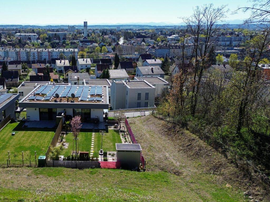 Moderne Wohnanlage mit gepflegtem Garten und Photovoltaikanlagen auf den Dächern, Blick über die Stadt.