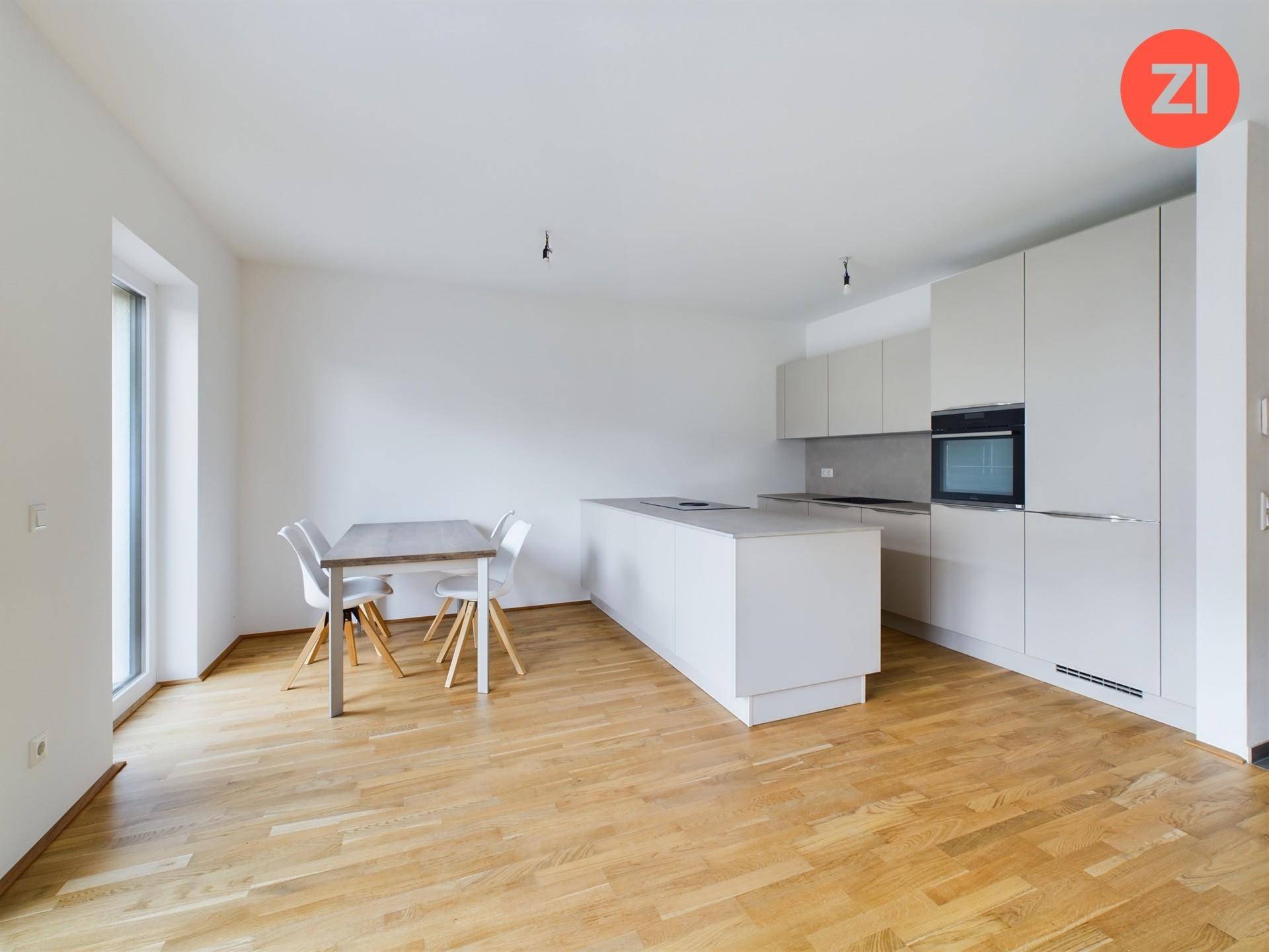 Moderne Einbauküche mit Kücheninsel, Essbereich und hellem Holzparkettboden.