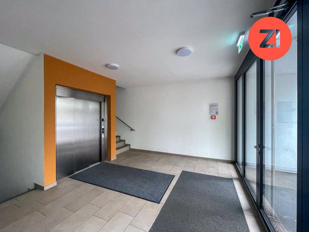 Heller Eingangsbereich mit Fliesenboden, Aufzug und Treppenhauszugang.