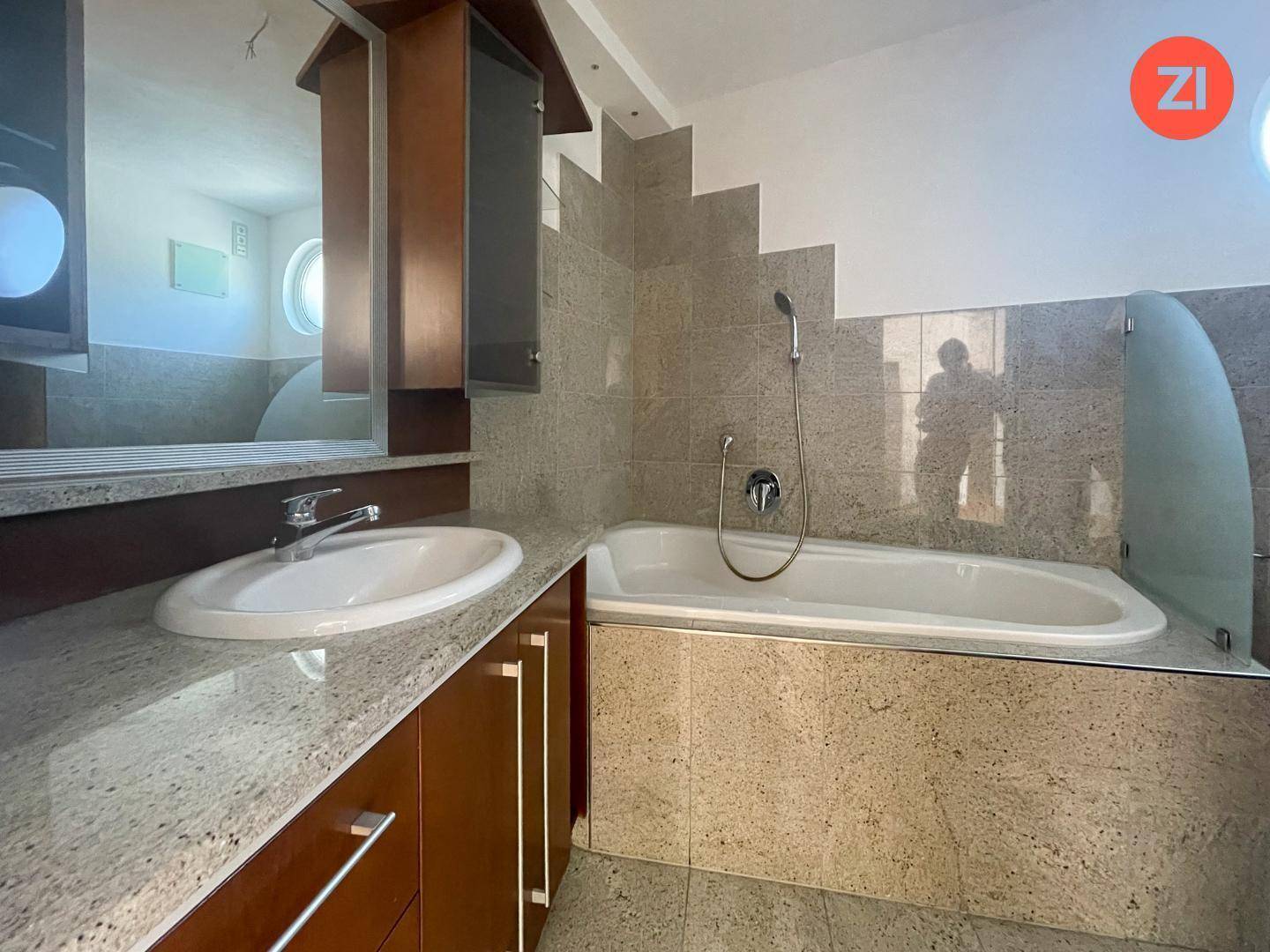 Elegantes Badezimmer mit Waschtisch, Spiegelschrank und Badewanne, alles in hochwertigen Fliesen gehalten.