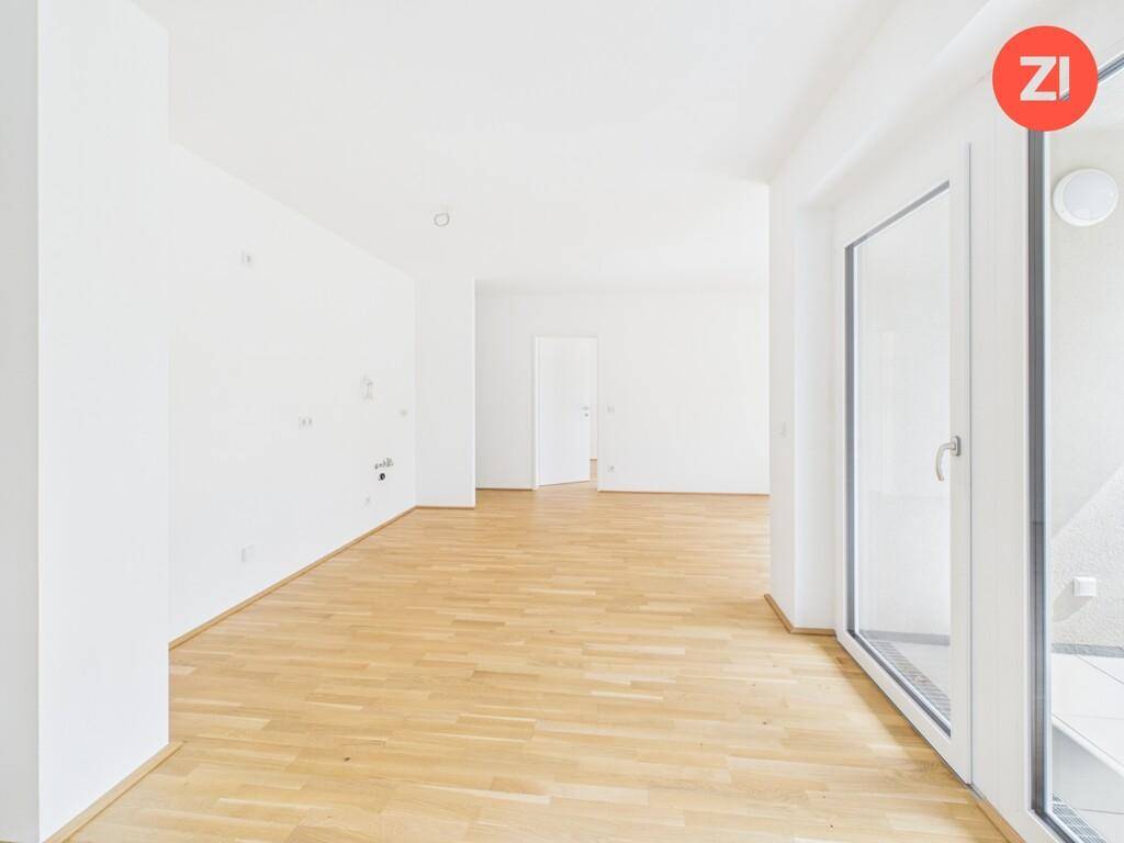 Heller, leerer Wohnraum mit Holzboden und großem Fenster, bereit zur individuellen Gestaltung.