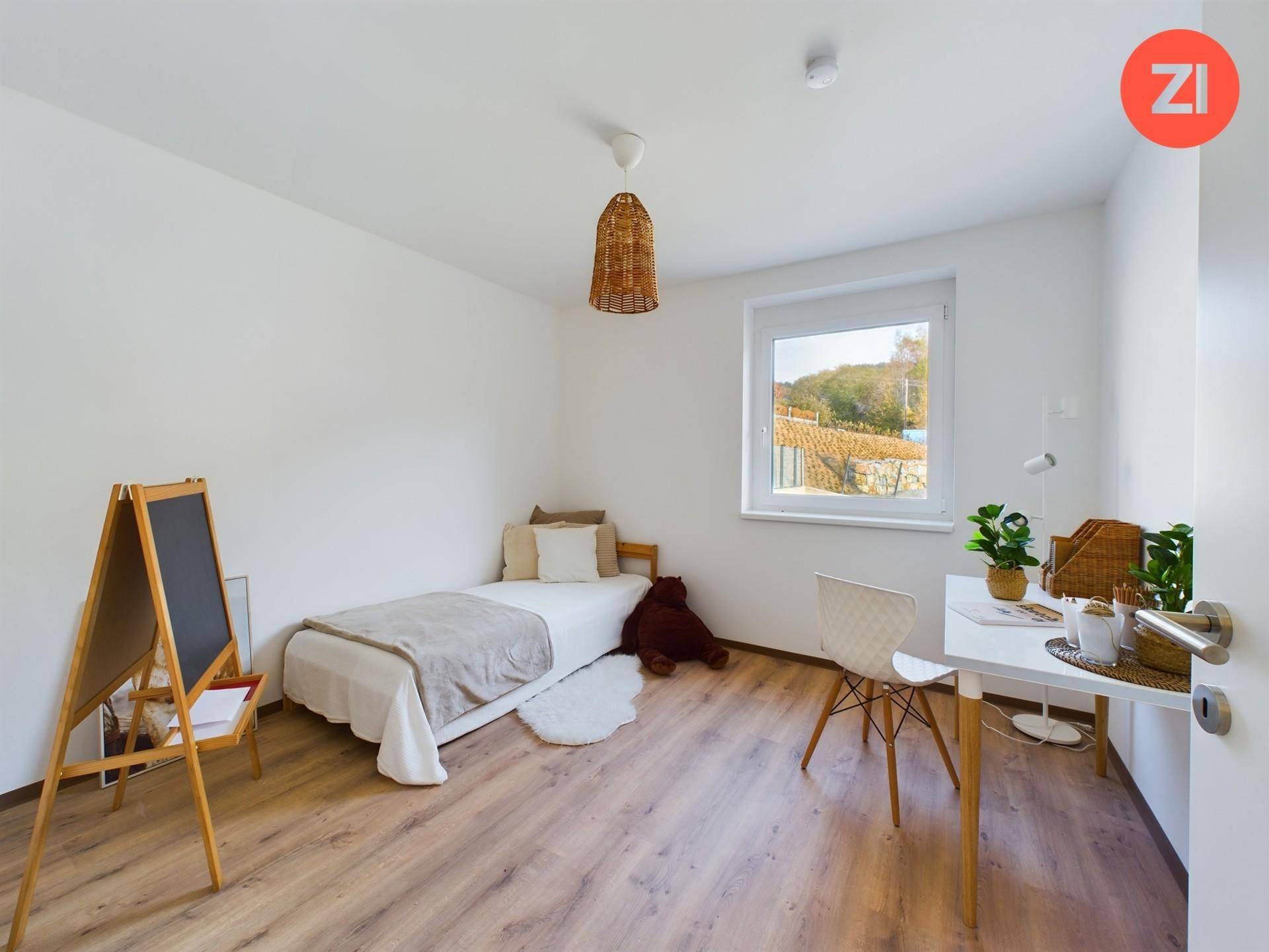 Helles Kinder- oder Gästezimmer mit Laminatboden, Schreibtisch und Blick ins Grüne.