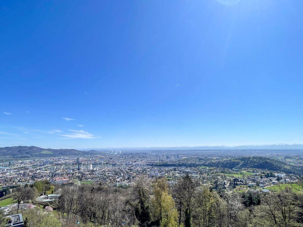 Weitläufiger Panoramablick über eine Stadt und die umliegende Landschaft unter einem klaren blauen Himmel.