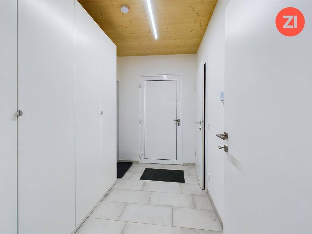 Heller Eingangsbereich mit praktischen Einbauschränken, Fliesenboden und Holzdecke.