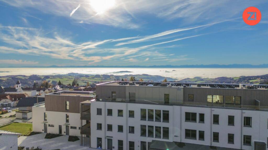 Luftaufnahme eines modernen Gebäudekomplexes mit weitem Blick über eine neblige Landschaft.