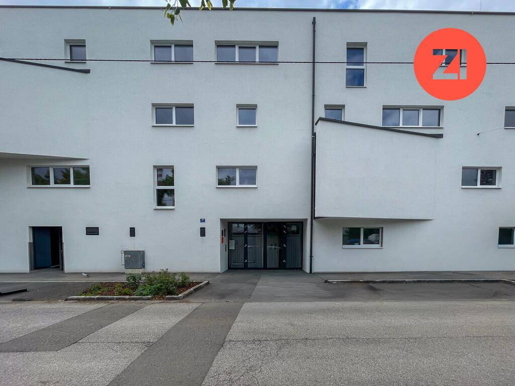 Moderne weiße Fassade eines Mehrfamilienhauses mit zahlreichen Fenstern und Eingangsbereich.
