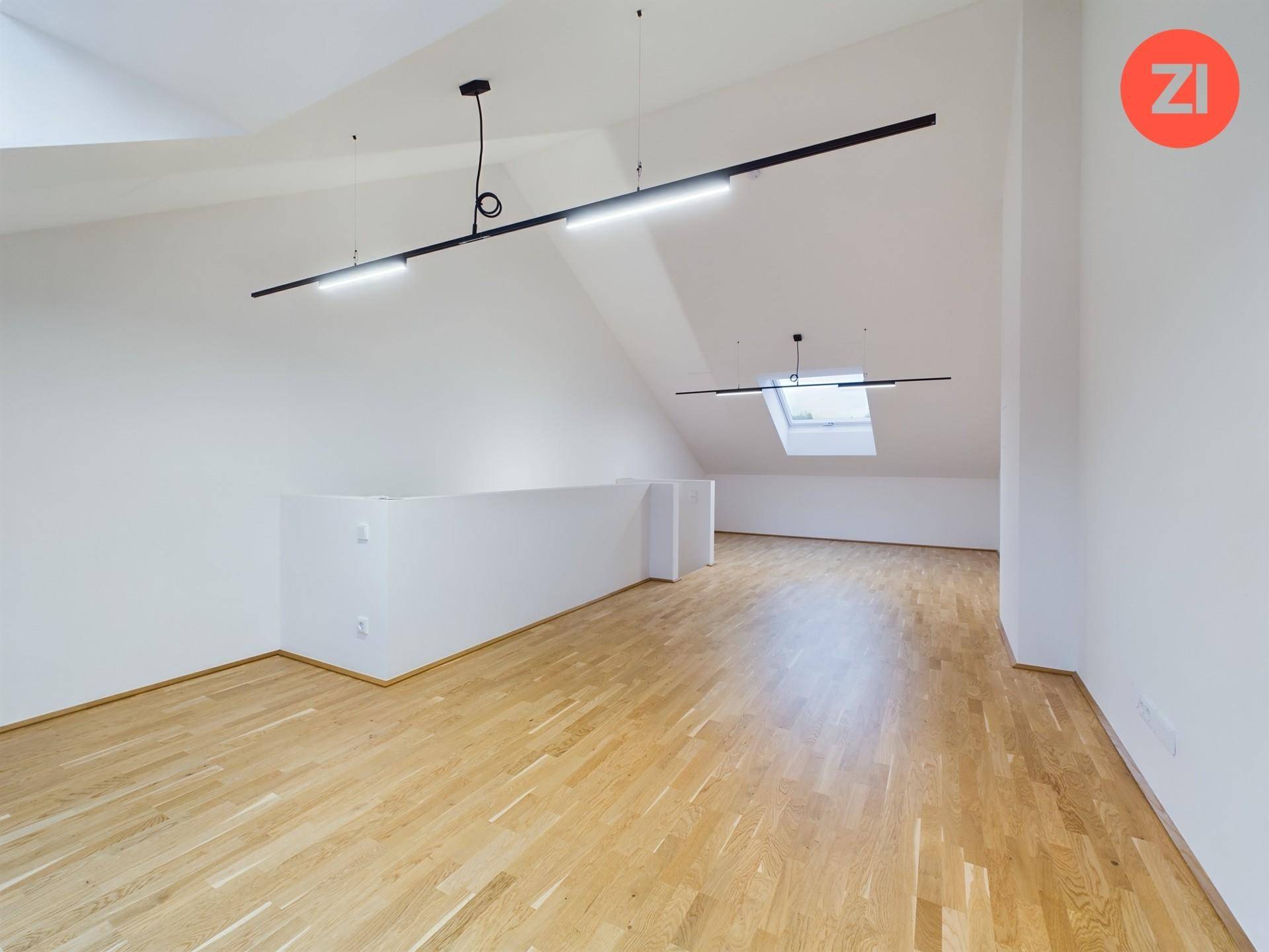 Heller und offener Dachbodenbereich mit Holzboden, Dachschrägen und modernen Lichtleisten.