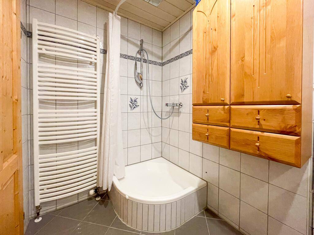Badezimmer mit Duschkabine, weißen Fliesen und beheiztem Handtuchhalter für Komfort.
