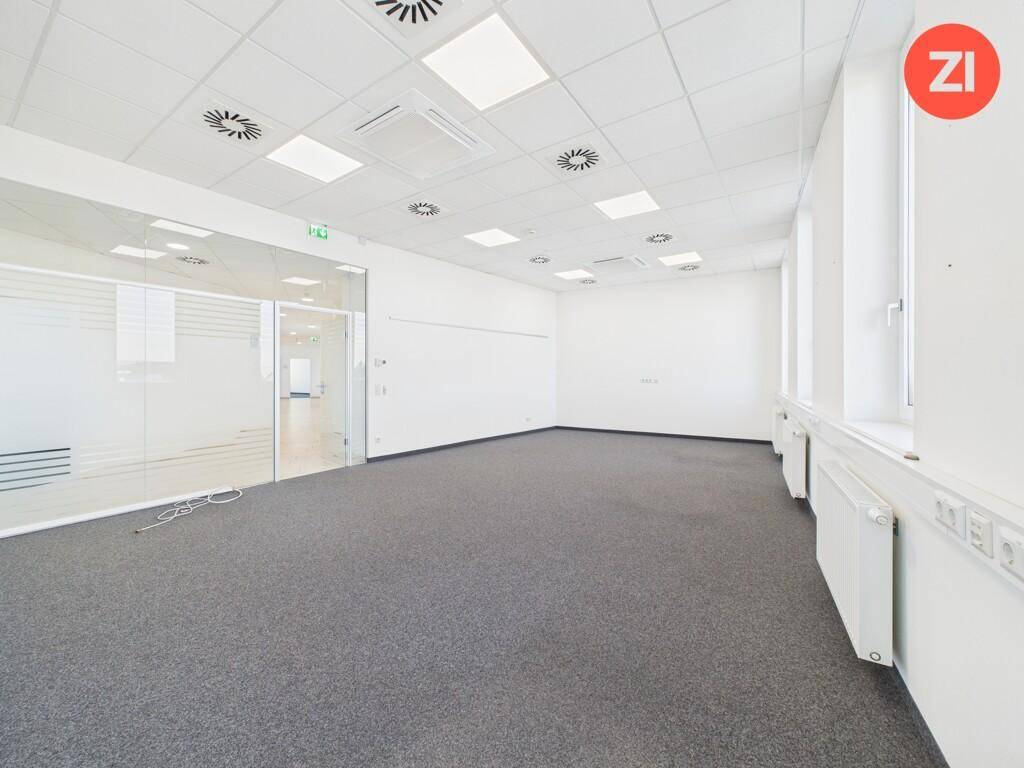Großes, helles Büro mit Teppichboden, abgehängter Decke und Glaswand zu einem weiteren Bereich.