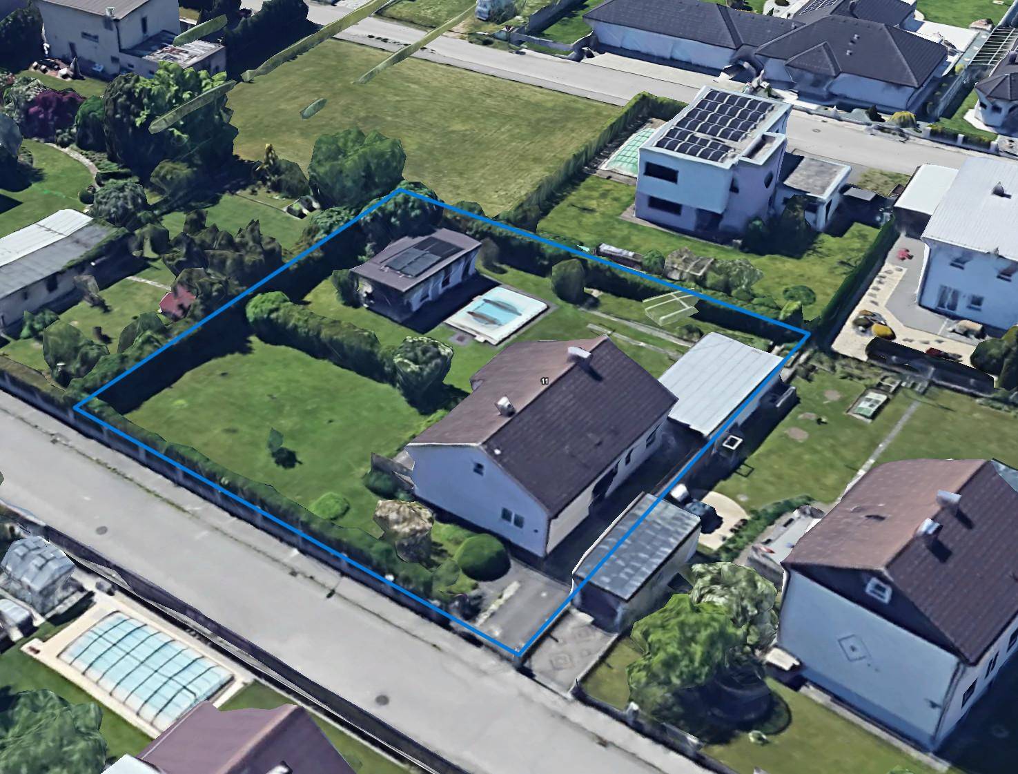 Luftaufnahme des Anwesens mit Haus, Garten, Pool und umliegender Nachbarschaft, blau umrandet.