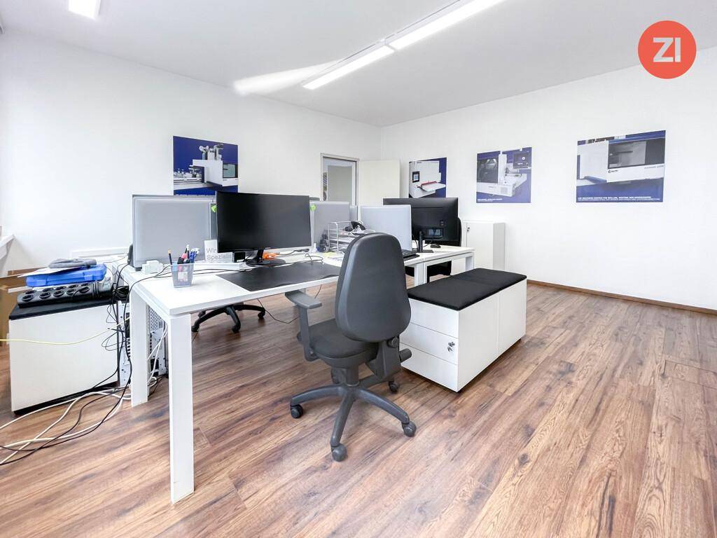 Detailansicht eines modernen Büros mit Arbeitsplätzen, Laminatboden und weißer Einrichtung.