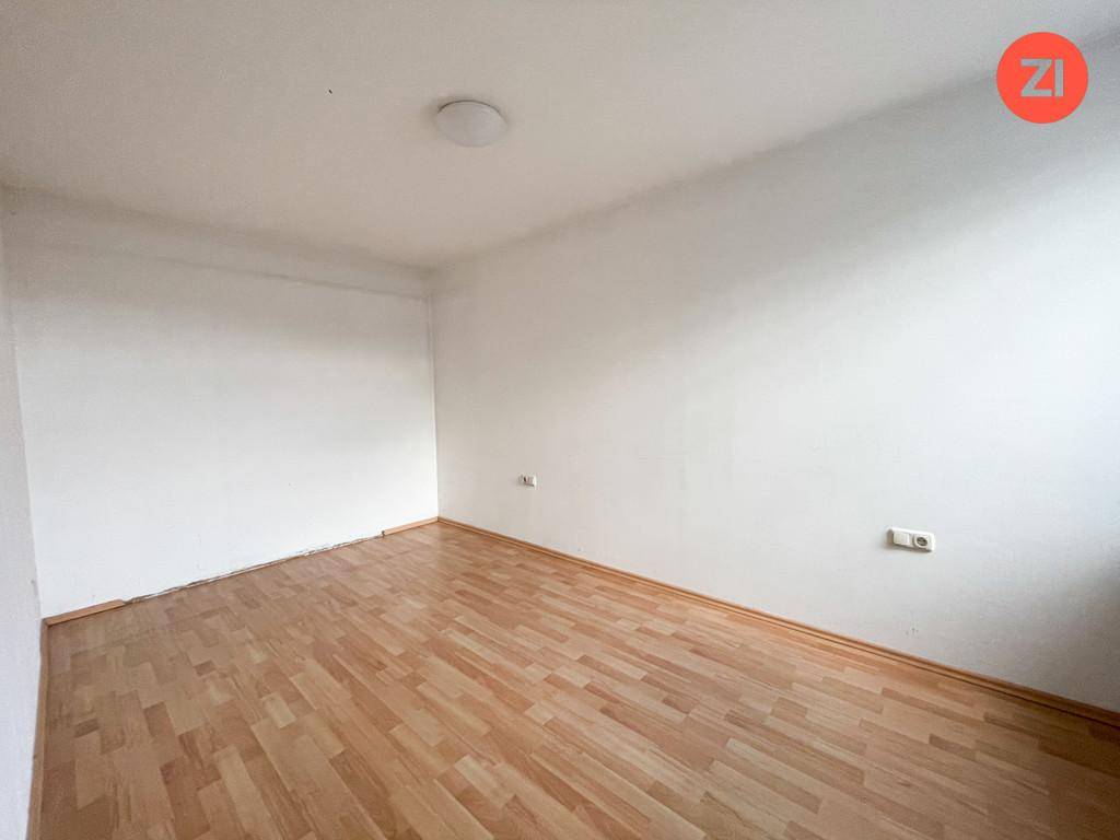 Leeres, helles Zimmer mit Holzfußboden und weißen Wänden, bereit zur individuellen Gestaltung.