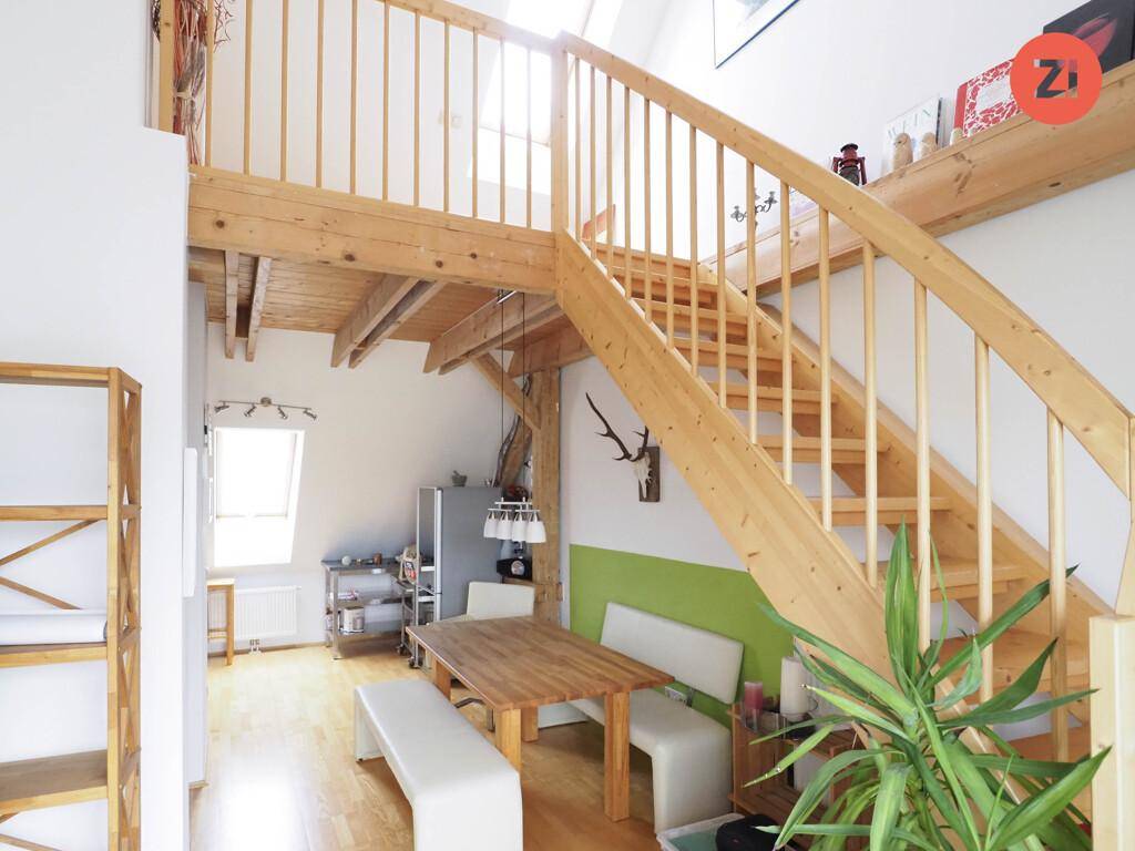 Offener Wohn- und Essbereich mit Holztreppe, Holzbalken und rustikalen Elementen.