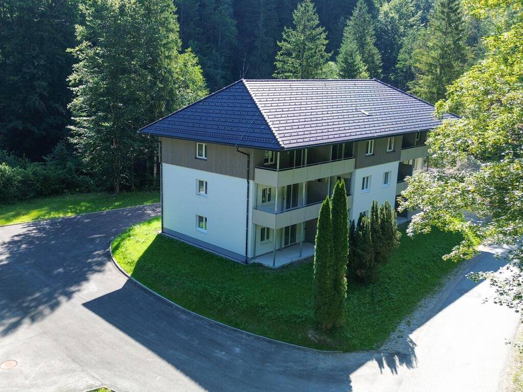 Luftaufnahme des modernen Gebäudes mit Satteldach und Balkonen, umgeben von Bäumen.