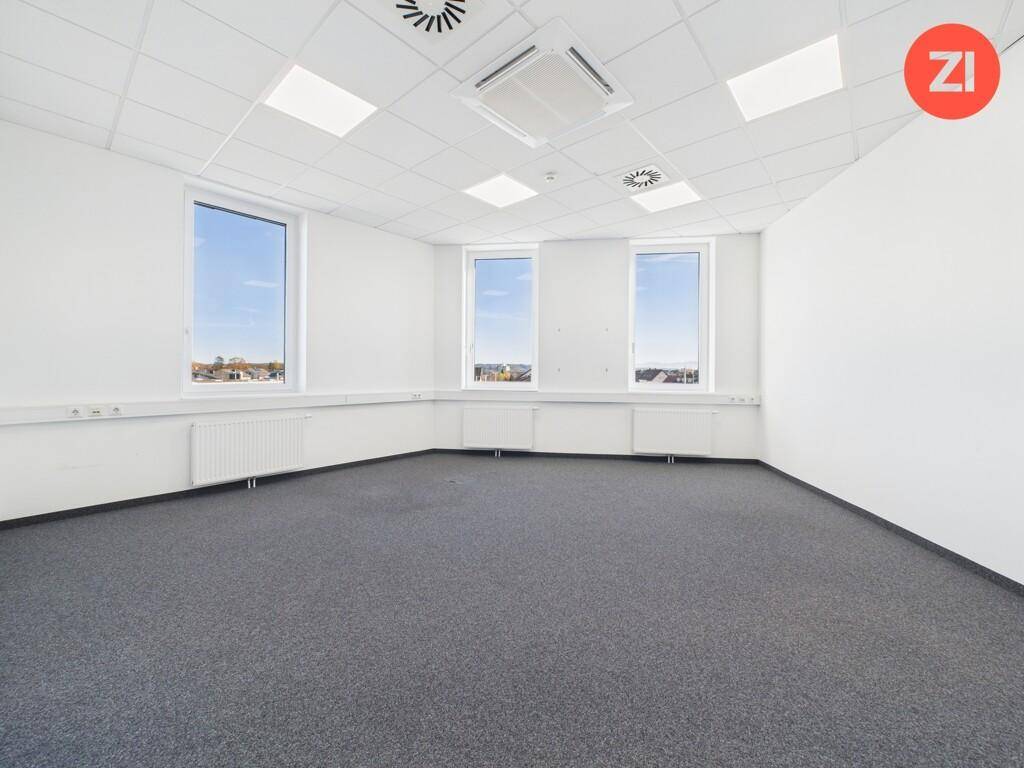 Helles, leeres Büro mit Teppichboden, vielen Fenstern und Klimaanlage an der Decke.