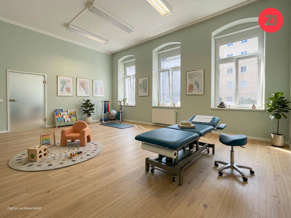 Freundlicher Therapieraum mit hellgrünen Wänden, einer Behandlungsliege und Holzboden. Große Fenster sorgen für viel Tageslicht.