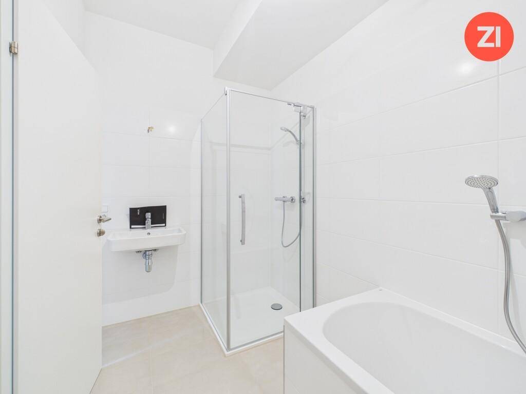 Modernes Badezimmer mit Badewanne, Duschkabine und weißen Fliesen an Wänden und Boden.