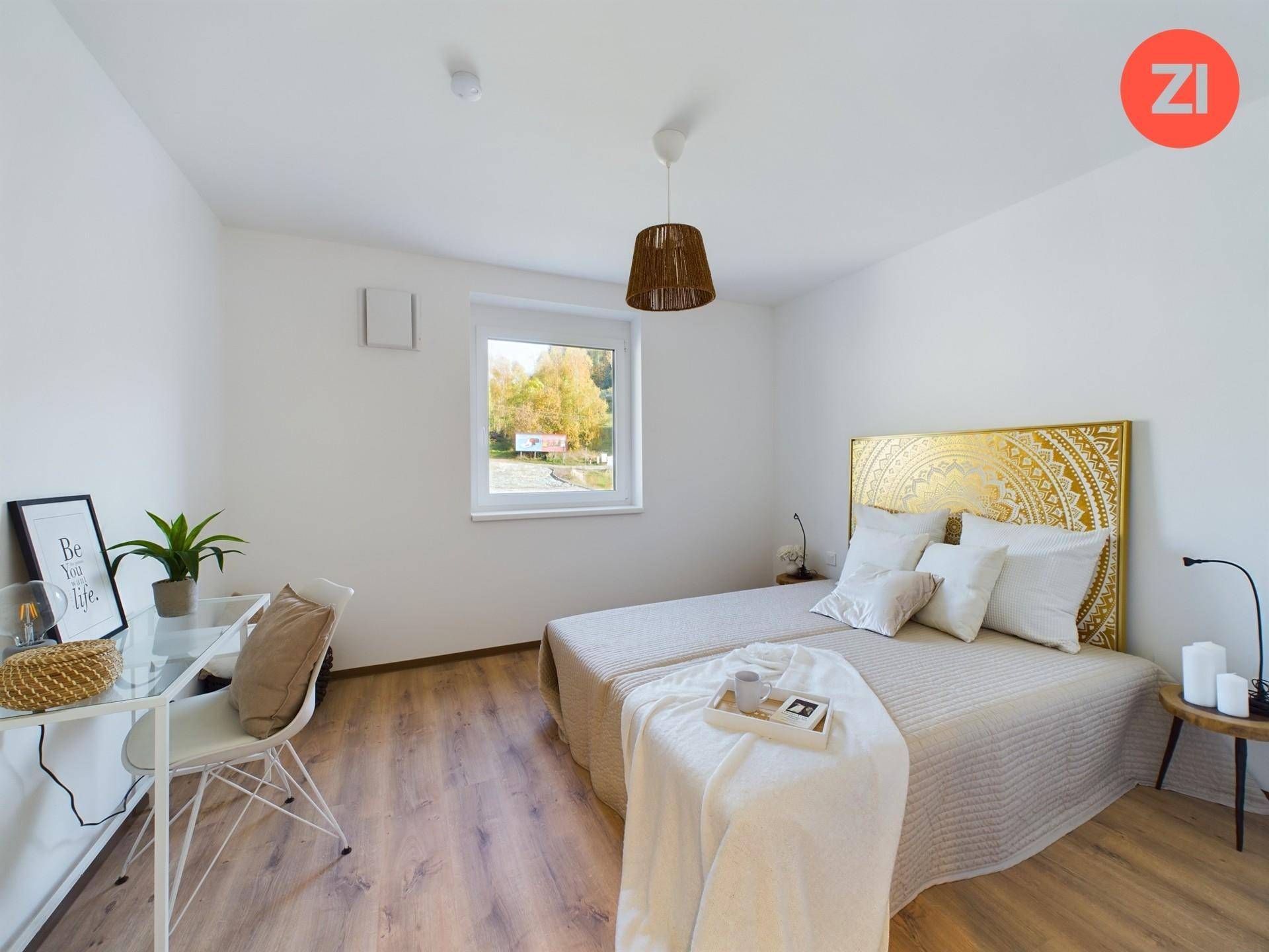 Gemütliches Schlafzimmer mit Laminatboden, großem Fenster und dekorativem goldenen Kopfteil.