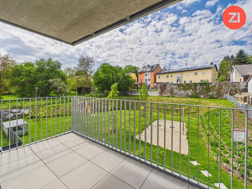 Geräumiger Balkon mit Fliesenboden und Metallgeländer, bietet einen weiten Blick ins Grüne.