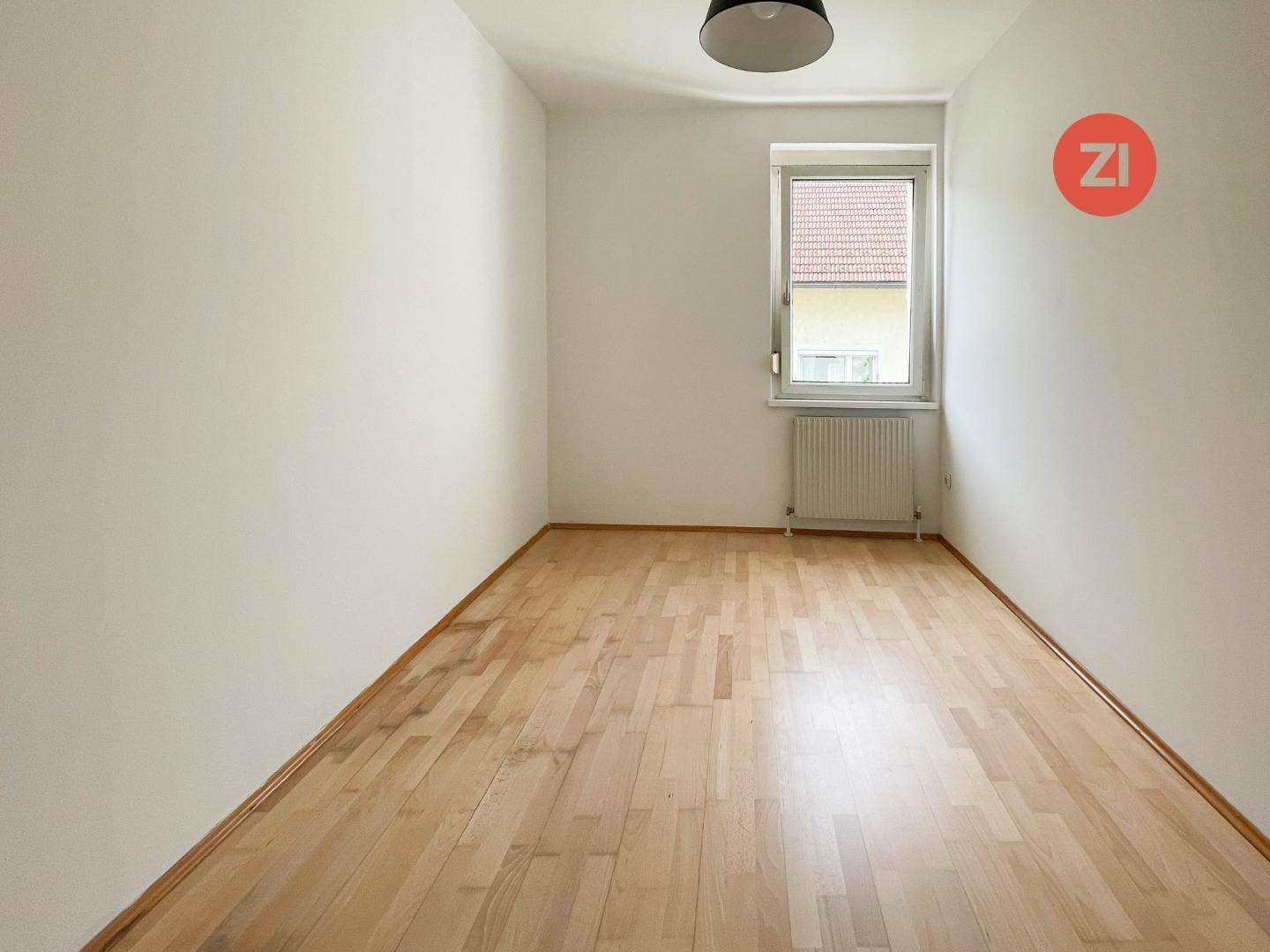 Gemütliches Schlafzimmer mit Holzboden und einem Fenster, das für natürliche Belichtung sorgt.
