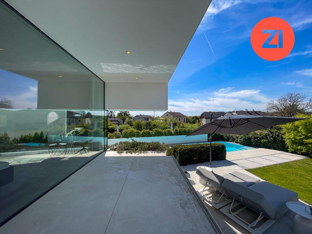 Sonnenterrasse mit Liegestühlen und direktem Blick auf den Pool und die umliegende Landschaft.