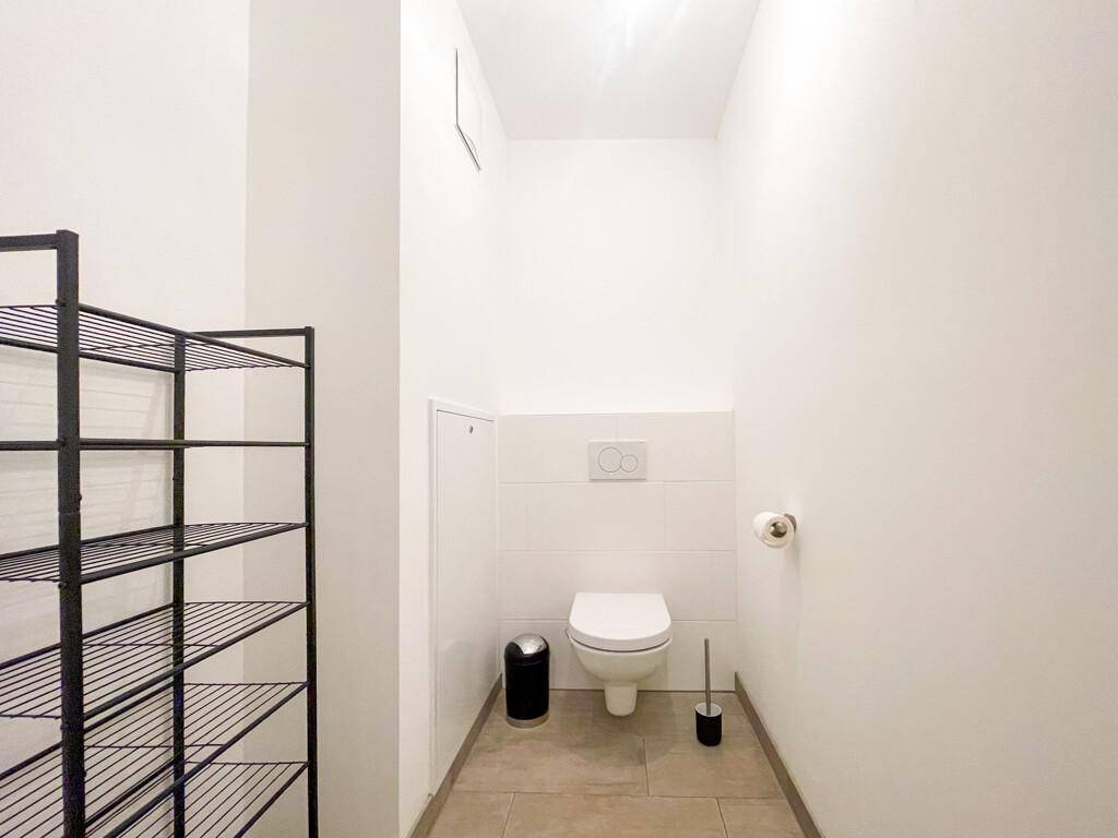 Funktionales Gäste-WC mit wandhängendem WC und hellen Fliesen am Boden und an der Wand.