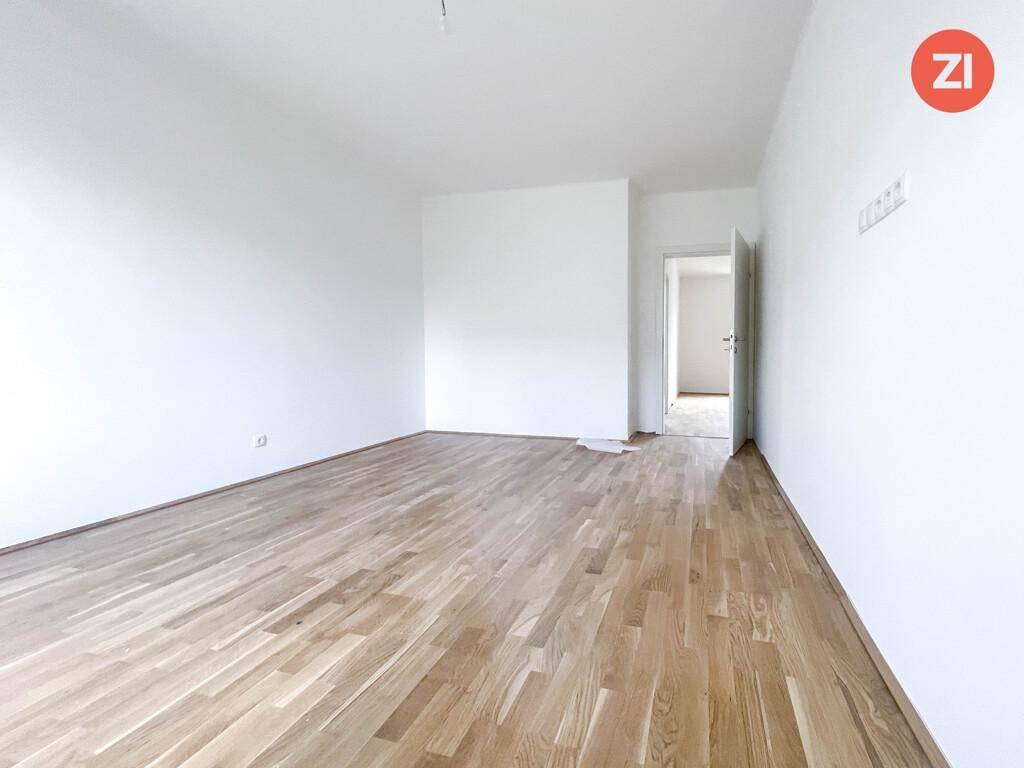 Geräumiges, leeres Wohnzimmer mit hellem Parkettboden und weißen Wänden, ideal für neue Bewohner.