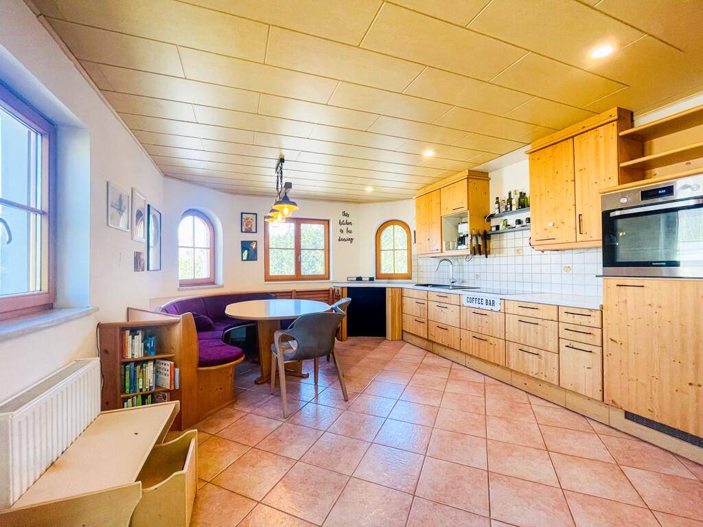 Gemütliche Wohnküche mit Holzeinbauten, Essbereich und Fliesenboden, ideal für Familien.